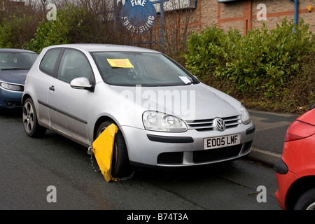 Wheel clamp on untaxed car with statutory notice attached to the windscreen. Stock Photo