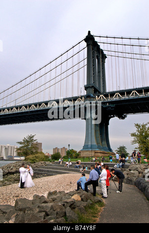 Wedding Couple being photographed by Manhattan Bridge in New York City with Manhattan in background Stock Photo