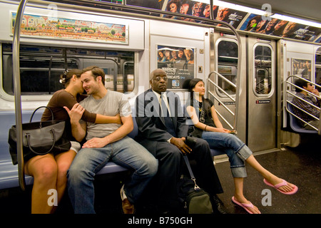 Oblivious of their surroundings a couple is openly affectionate in a New York City subway car as fellow passengers ignore them Stock Photo