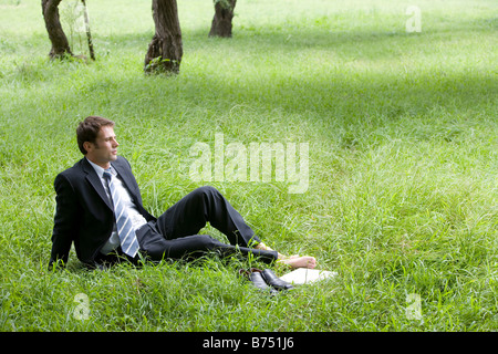 One mid adult man reclining on lawn laptop and dress shoes aside Stock Photo