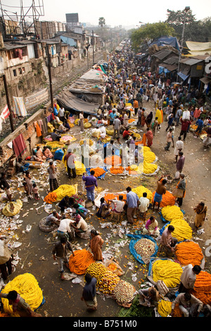 People buy and sell flowers at the colourful Mullick Ghat Flower Market near to the Howrah Bridge in Kolkata, India. Stock Photo