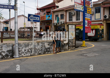 A couple waiting to cross a road in the old town, Melaka, Malaysia Stock Photo