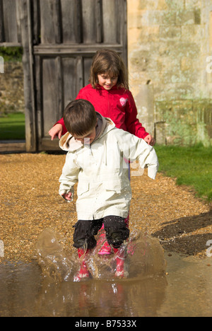 Little Girl and Boy Jumping in a Puddle Stock Photo