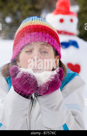 Thirteen year old girl blowing snow toward camera, Winnipeg, Canada Stock Photo