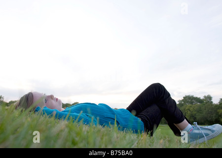 Eight year old girl lying on back in grass looking upward, Winnipeg, Manitoba, Canada Stock Photo