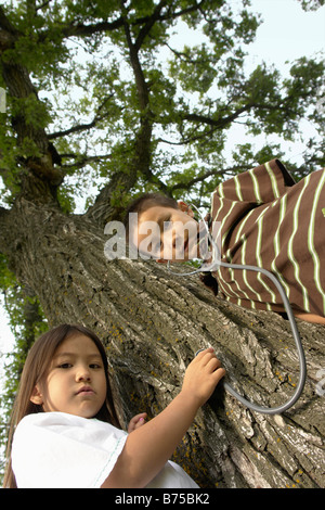 Low angel, five and seven year old sister and brother with stethescope on tree, Winnipeg, Canada Stock Photo