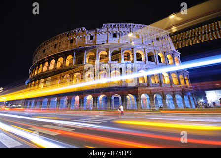 A night shot of Rome's famous and historic Coliseum, with lights of passing traffic streaking by in the foreground. Stock Photo