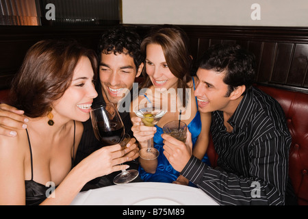 Two couples holding glasses of wine and smiling in a bar Stock Photo