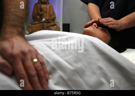 a couple performing reiki on a young attractive woman Stock Photo