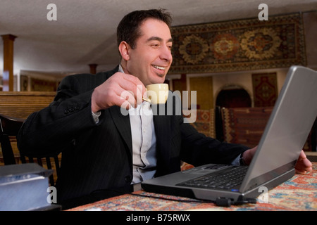 Businessman using a laptop in a restaurant and smiling Stock Photo