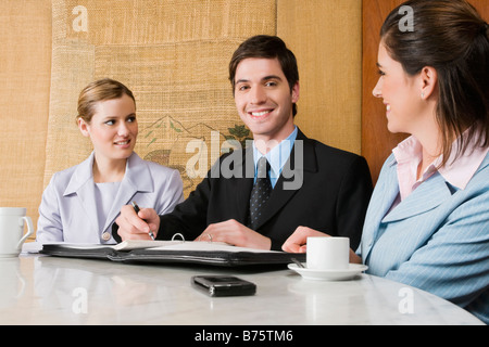 Two businesswomen and a businessman discussing in a cafe Stock Photo