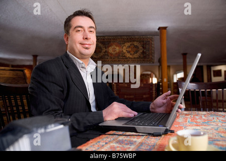 Portrait of a businessman using a laptop at a restaurant and smiling Stock Photo