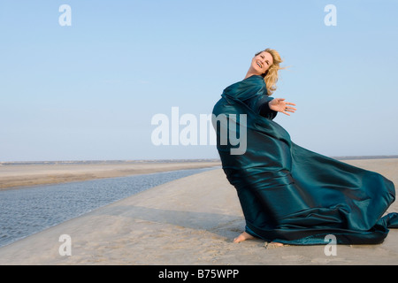 Side profile of a pregnant woman standing with her arms outstretched and smiling Stock Photo