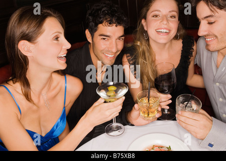 Two young couples sitting at a table and enjoying cocktail Stock Photo