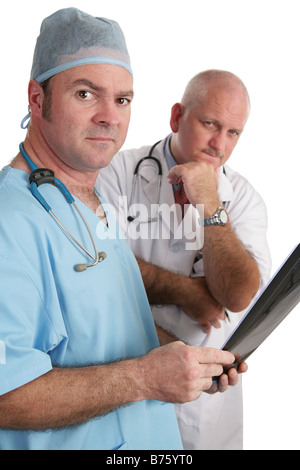 Two doctors examining xrays They are looking at the camera with serious expressions Stock Photo