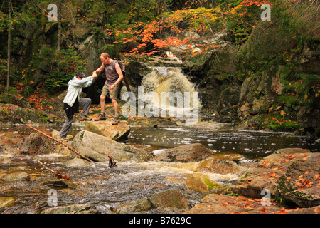 Hikers Cross Cascade Brook on Cascades-Basin Trail, Appalachain Trail, Lincoln, New Hampshire, USA Stock Photo