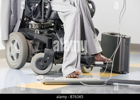 Businessman with Cerebral Palsy working on a computer with his foot Stock Photo