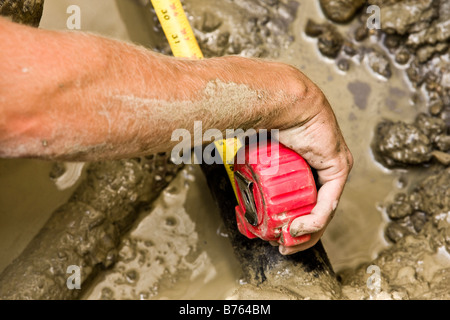 Construction worker using measuring tape in mud Stock Photo