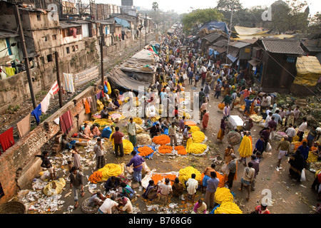 People buy and sell flowers at the colourful Mullick Ghat Flower Market near to the Howrah Bridge in Kolkata, India. Stock Photo