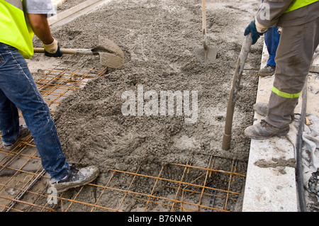 Two workers pour a vibrated reinforced concrete slab. Stock Photo