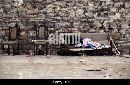 A homeless man lies asleep early in the morning on a discarded sofa in a courtyard in Sultanahmet, Istanbul. Stock Photo