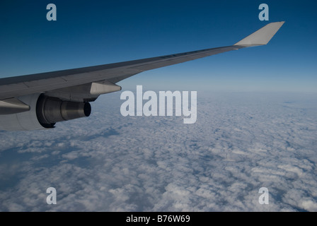 View of clouds and aircraft wing through window of Air Philippines Boeing 747 Jumbo jet Stock Photo