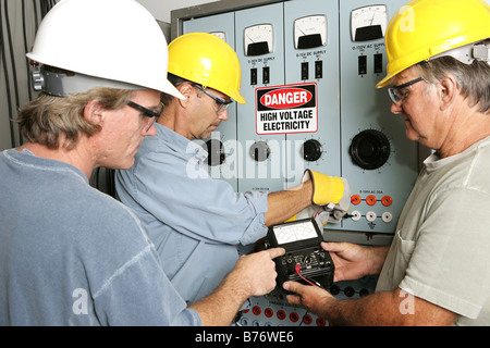 Group of electricians using an OHM meter to test voltage in an industrial power center All work performed according to code Stock Photo
