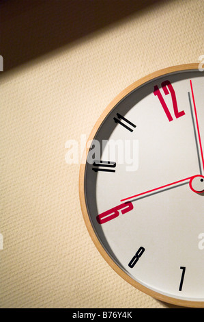 Clock of contemporary design showing a few minutes past nine o'clock. On textured plain background Stock Photo