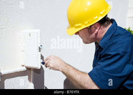 Electrician doing repairs inside and electrical box on the outside of a home Model is a licensed electrician Stock Photo