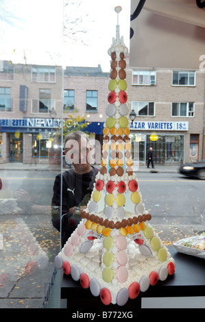 A man looking through a shop window at an Eiffel Tower made from sweets Stock Photo