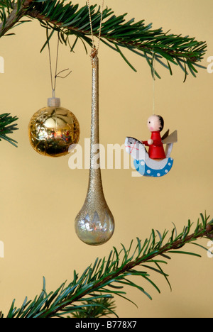 Ball, teardrop and angel on rocking horse Christmas tree ornaments and branches in form suggestive of a face, England Stock Photo