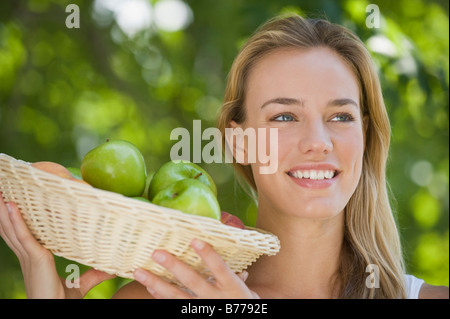 Close up of woman holding basket of apples Stock Photo