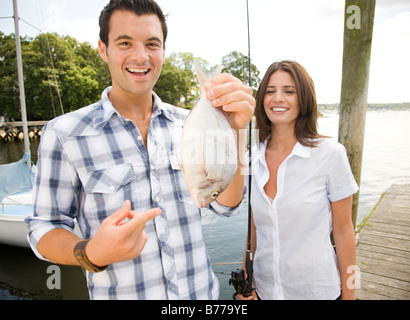 Portrait of couple holding freshly caught fish Stock Photo