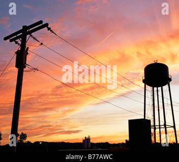 Water tower and telephone pole against sunset sky Stock Photo