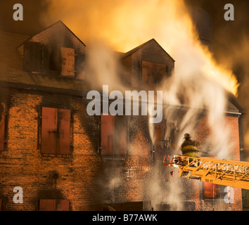 Firefighter on crane fighting building fire Stock Photo