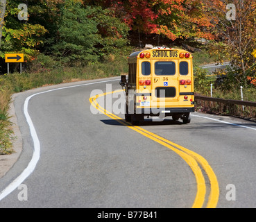 School bus driving down rural road Stock Photo