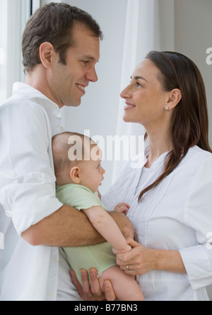 Couple standing face to face holding baby son Stock Photo