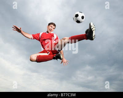 Soccer player kicking soccer ball mid-air Stock Photo