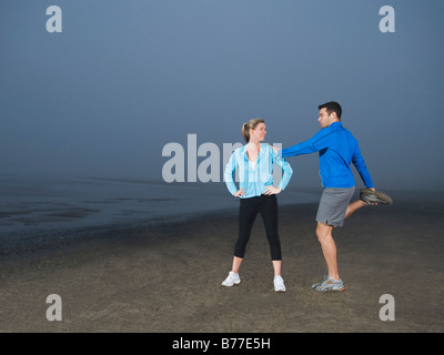 Couple stretching on beach Stock Photo