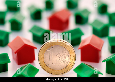 Miniature houses and one euro coin, symbolic of building society savings Stock Photo
