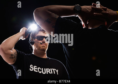 Security guard shining flashlight on man Stock Photo