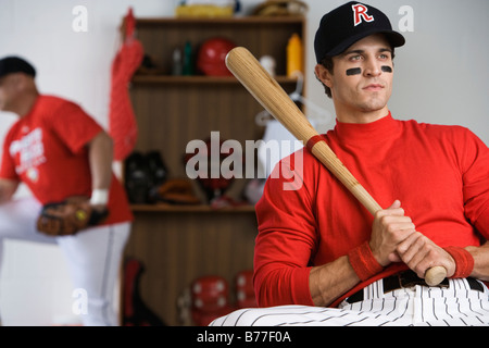 Baseball player holding bat locker room Stock Photo
