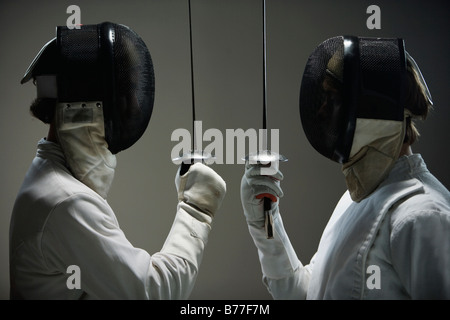 Fencers masks facing off fencing foils Stock Photo