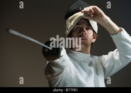 Man pointing fencing foil and lifting mask Stock Photo