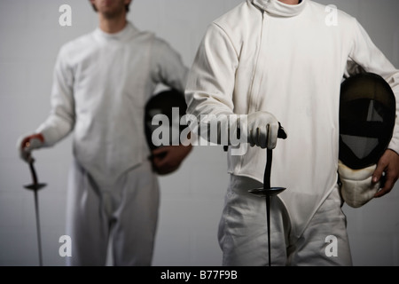 Portrait of fencers holding masks and fencing foils Stock Photo