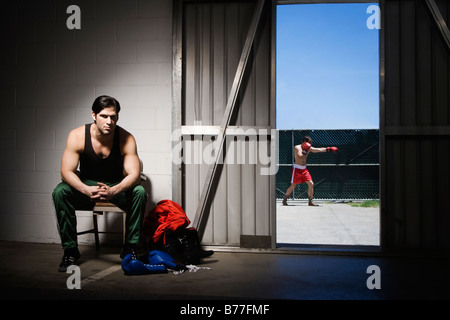 Man sitting on stool by doorway boxer background Stock Photo