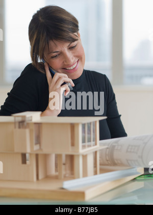 Architect talking on cell phone next to building model Stock Photo