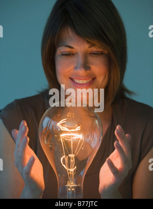 Woman holding hands around large light bulb Stock Photo