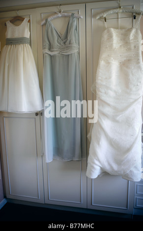 Brides and bridesmaids dresses hanging on wardrobe Stock Photo