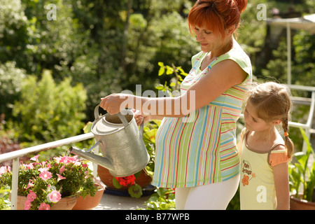 Girl and pregnant woman watering flowers Stock Photo